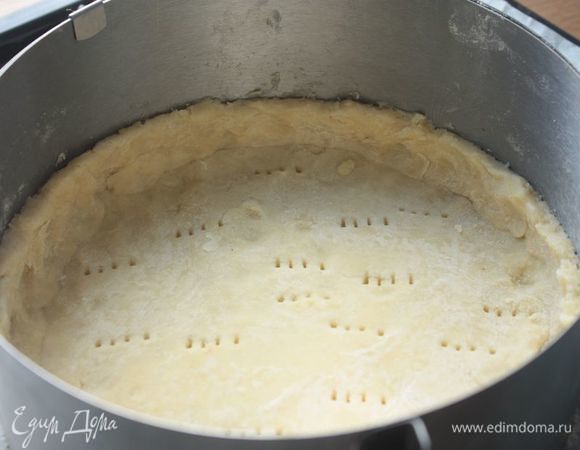 Охлажденное тесто достаем из холодильника и раскатываем на пергаменте. С помощью формы для запекания вырезаем круг-основание, а затем делаем невысокие бортики. Обязательно наколите основание пирога вилкой.