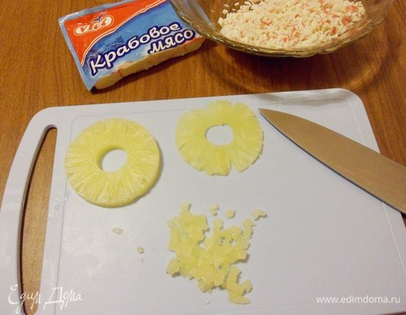 Разрезать каждый кружок ананаса вдоль на 2 тонкие части и затем нарезать мелкими кубиками.