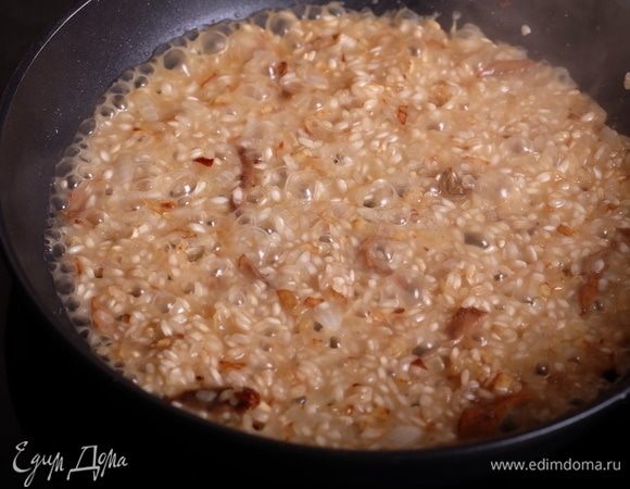 Добавить первый половник бульона и, опять же аккуратно помешивая рис, добиться практически полного его впитывания. Добавить следующий половник и т.д.