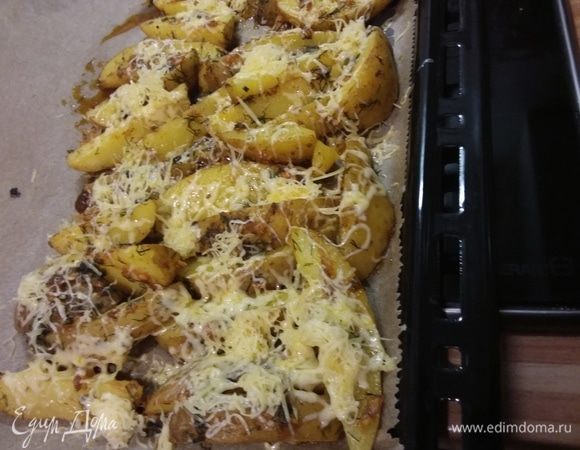 Через 20 минут вынуть противень и посыпать картофель натертым сыром. Запекать еще минут 15 до образования румяной корочки. 
