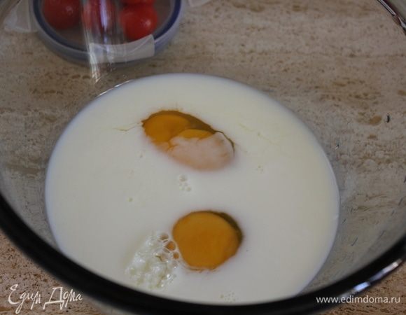 В стекляную миску влить молоко, вбить 2 яйца.