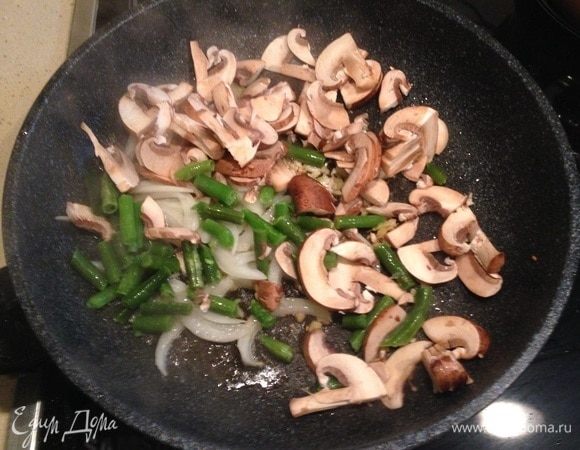 Выложить лук, грибы и фасоль. Обжарить несколько минут и убавить огонь.