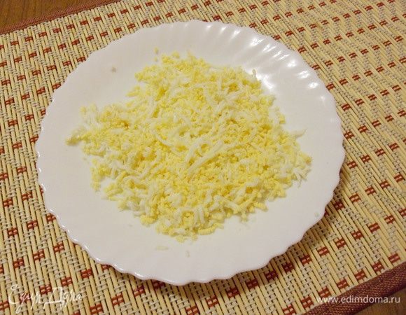 Отварные и охлажденные яйца почистить и натереть на средней терке.