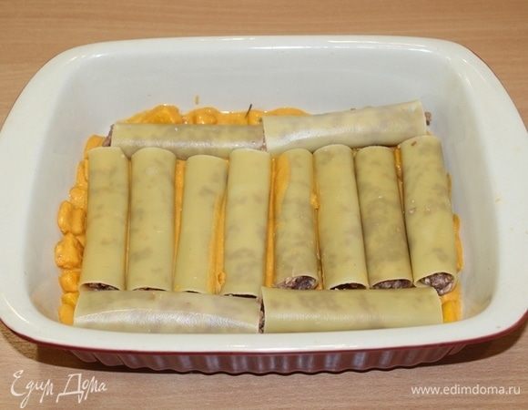 Выложить немного соуса на дно формы, затем выложить каннеллони.