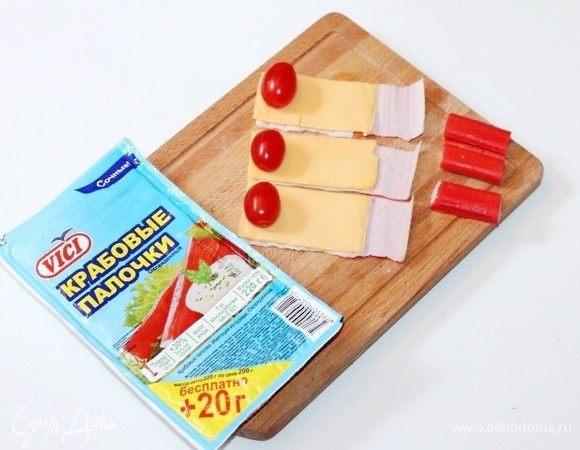 Берем 3 крабовые палочки Vici и разрезаем каждую на две части. Раскручиваем половинки палочек. Кладем по 1/2 пластины сыра и помидорчики черри. 
