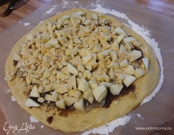 На тесто нанести масло с сахаром и корицей, яблочный мусс, распределить яблоки, посыпать крошкой печенья. Всю начинку распределить по кругу, оставляя свободными края. 