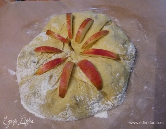 Перенести на пергаменте в форму для запекания размером 24 см в диаметре. Украсить ломтиками яблока. Накрыть пленкой и оставить в теплом месте на отдых на час. 