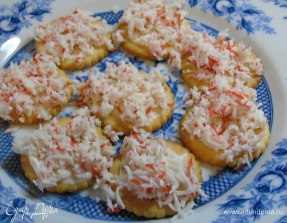 Выкладываем половину натертых крабовых палочек на смазанный майонезом крекер.