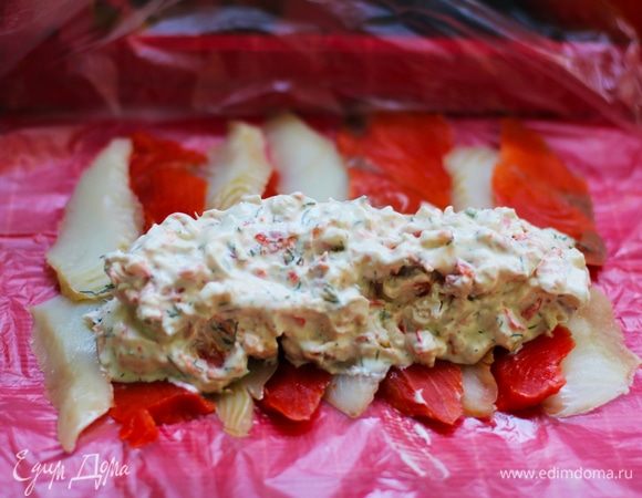 Расстелите на столе коврик для суши. Застелите его пленкой. Выложите на пленку нарезанный пластинами лосось (пласты должны слегка перекрывать друг друга).
На лосось выложите рыбный мусс вдоль длиной стороны.