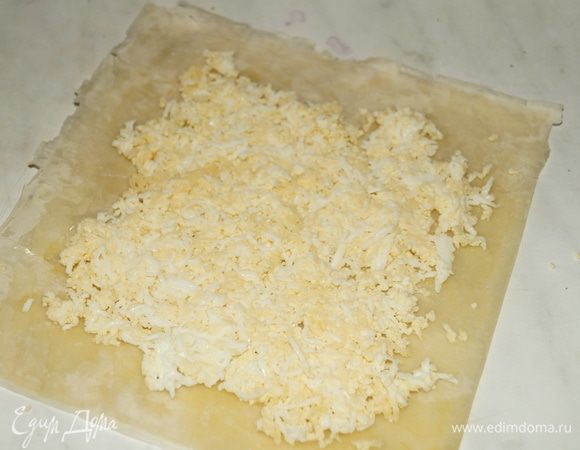 Часть яично-сырной начинки выложить на пласт теста, оставив по краям не заполненные промежутки.