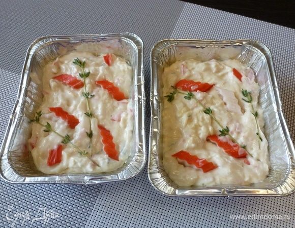 Формы смажем маслом и выложим тесто. Сверху на тесто разложим кусочки крабовых палочек и слегка вдавим их в тесто. 