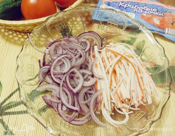 В салатник выложить нарезанные крабовые палочки и лук.