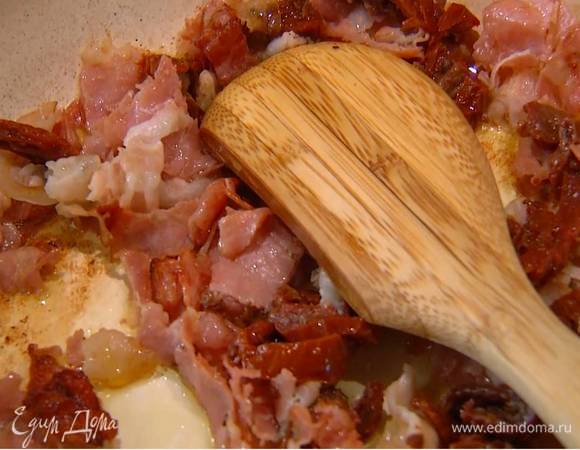 Сковороду с обжаренной ветчиной снять с огня, добавить вяленые помидоры и все перемешать.