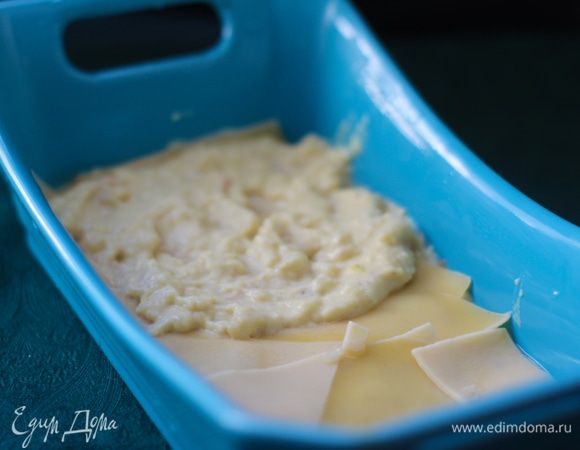 Смазать дно формы тонким слоем соуса, положить в один ряд листы лазаньи, сверху — четверть соуса, разровнять.