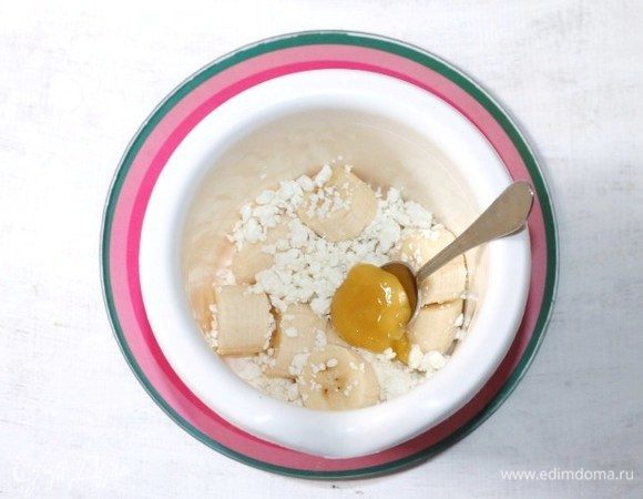 В чашу блендера выложить клюкву, творог, очищенный и порезанный банан, мед.
