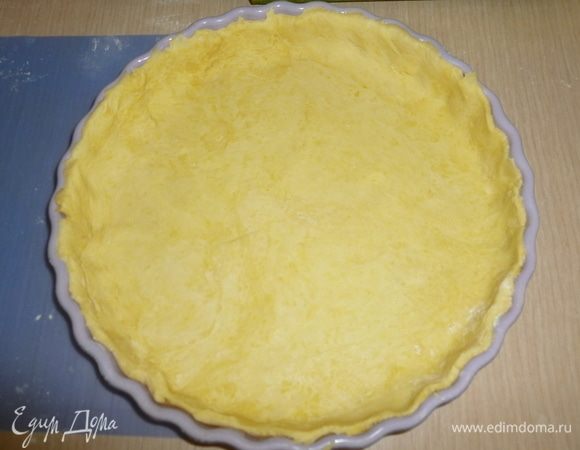 Тесто достать, раскатать по размеру немного большему диаметра формы. Аккуратно перенести в форму и сформировать бортики. Накрыть пленкой и убрать в холодильник на 30 минут. Разогреть духовку до 180°С. Поставить форму в духовку на 20 минут.