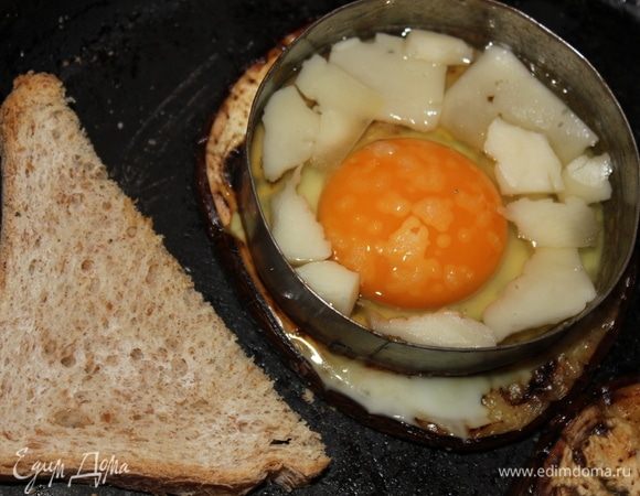 На белую часть яйца выложить кусочки сыра (в моем случае, это сыр азиаго, но подойдет  российский, голландский), посолить. Я сразу же выложила кусочки хлеба, подсушить на сковороде. Закрыть крышкой, готовить 3 минуты на медленном огне. Не забудьте перевернуть хлеб.
