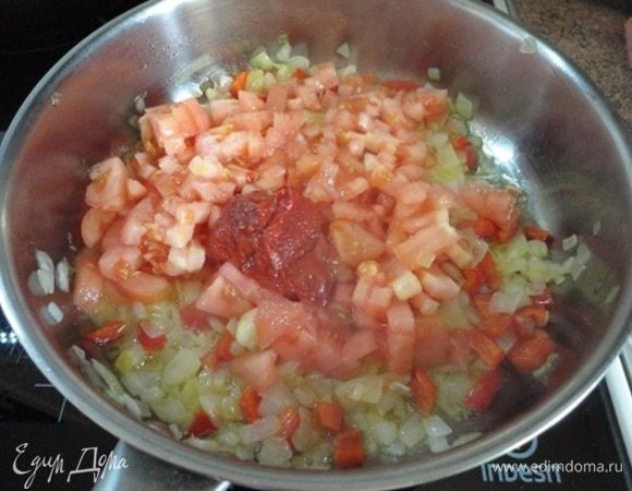 Помидоры (2 штуки) очистить от кожицы с помощью кипятка, нарезать кубиками и вместе с томатной пастой добавить к остальным овощам на сковороде. Обжаривать 4-5 минут.