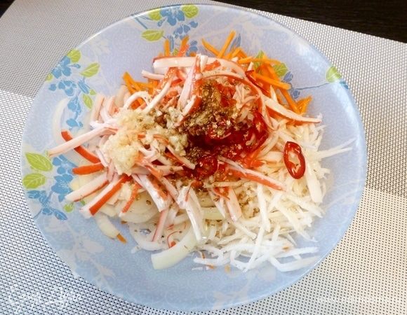 На сковороде прогреем масло с чили и размятым в крупную крошку кориандром. Выльем на овощи. Чеснок выдавим через пресс.