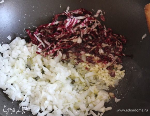 На разогретую глубокую сковороду с оливковым маслом, или низкую кастрюлю, выложить мелко порубленный лук (лучше использовать красный), 1 зубчик мелко порубленного чеснока и нарезанный цикорий. Пассеровать 3 минуты.