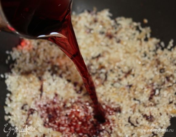 Влить вино, быстро перемешать, и буквально, сразу же, накрыть крышкой. Важно! Рис должен полностью впитать вино! Иначе, вкус ризотто в конце немного испортится. Через 1–1,5 минуты уберите крышку и постоянно перемешивайте рис до полного испарения вина. Он уже на этом этапе начнет приобретать рубиновый цвет.