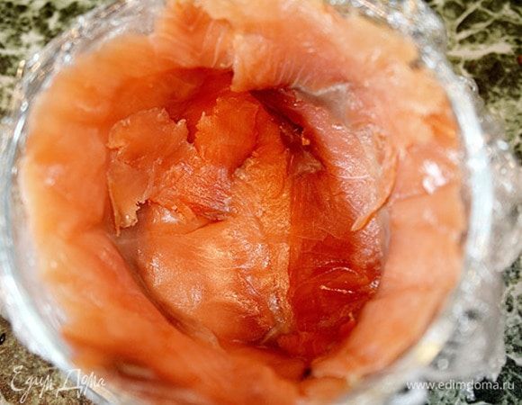 Миску выстелить пленкой и выложить по всей поверхности ломтики соленой рыбы. 
