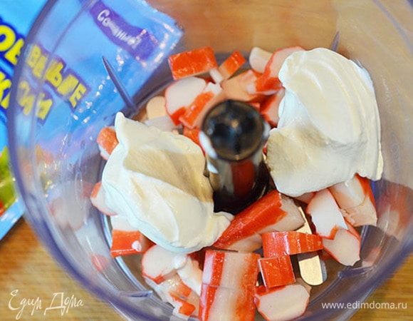 В чашу блендера положить крабовые палочки, сметану и измельчить с помощью блендера.