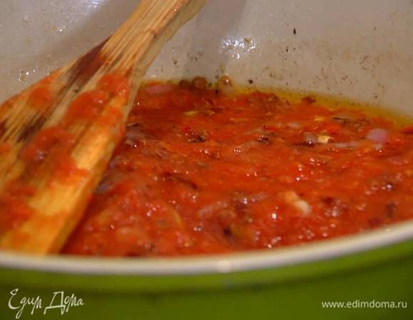 В сковороду с луком и чесноком добавить измельченные томаты, немного соли и сахар, все перемешать и прогреть на небольшом огне.