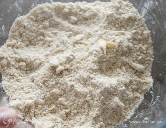 Добавить щепотку соли и нарезанное кубиками холодное сливочное масло. Перетереть массу руками в крошку.