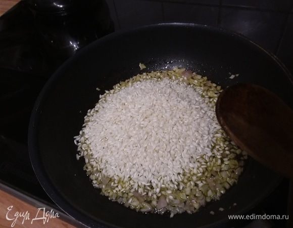 Выложить рис к луку, перемешать, обжарить коротко. 