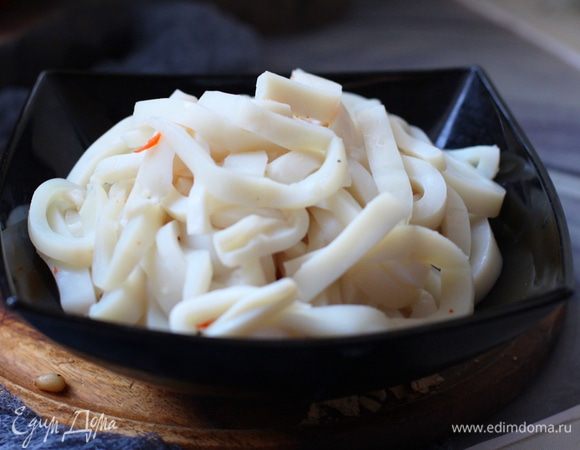 Тушки кальмаров (чищеные, разделанные) бросить в кипяток и оставить на 1 минуту (не варить). Откинуть на сито. Порезать кольцами или полосками.