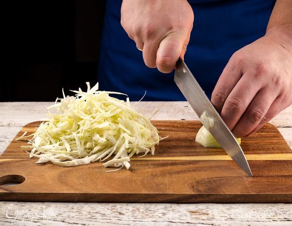 Приготовьте основу для запеканки. Измельчите лук и нашинкуйте капусту. В сковороду налейте немного оливкового масла и обжарьте лук до золотистого цвета.
