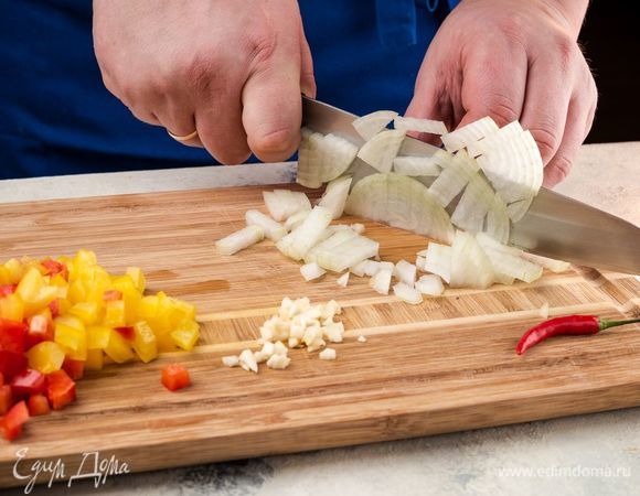 Нарежьте мелко лук и чеснок, небольшими кусочками болгарский перец. Перец чили — тонкими колечками. В сотейнике нагрейте оливковое масло, обжарьте лук и чеснок. Добавьте молотый перец чили и продолжайте готовить, постоянно помешивая. 
