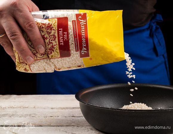 Добавить к луку рис «Гигант» ТМ «Националь», обжарить, пока рис не впитает масло.
