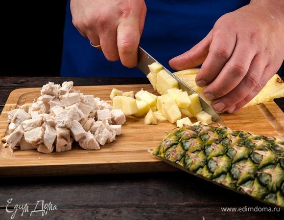 Куриное филе отварите, остудите и нарежьте кубиками. Ананас хорошо промойте, обсушите бумажным полотенцем, разрежьте пополам, из одной части выньте мякоть и нарежьте ее кубиками.