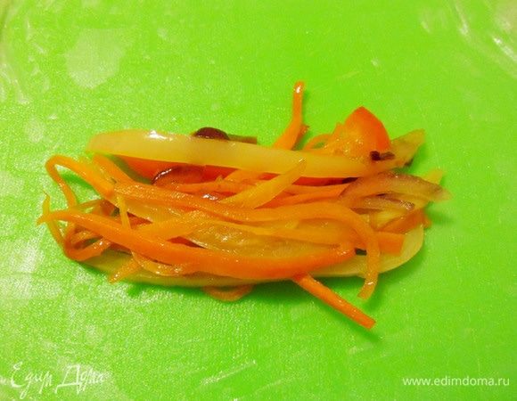 Рисовую бумагу разложить на разделочной доске. На середину листа положить подготовленную начинку.