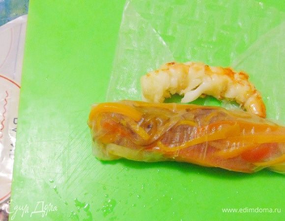 Завернуть края рисовой бумаги конвертиком. Следом положить креветки и завернуть лист рисовой бумаги до конца. Креветка должна быть видна сквозь рисовую упаковку (бумагу).