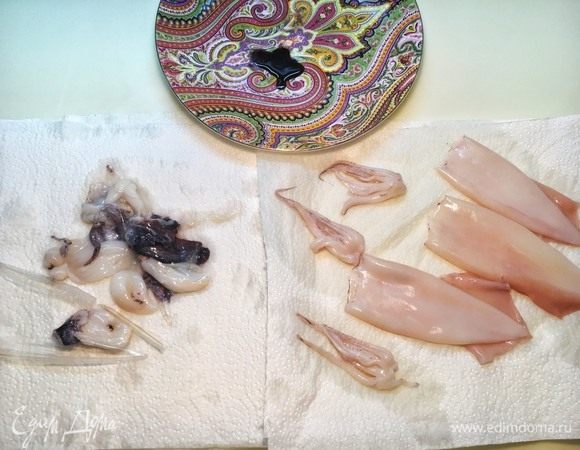 Вымойте кальмары, аккуратно оторвите щупальца (внутри мешочек с чернилами, он может брызнуть, если его повредить), снимите кожу, выньте хрящи, достаньте внутренности. Отрежьте от щупалец мешочек и выдавите из него чернила в стаканчик или на тарелку. Чернила будут служить краской для тюили, если вы решите делать декор. Из щупалец выдавите клюв, находящийся посередине, и очистите их от кожи. Хорошенько промойте кальмара и щупальца еще раз.