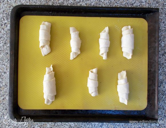 Укладываем круассаны на противень с силиконовым ковриком или на смазанную маслом бумагу для выпечки. Сверху накрываем их бумагой для выпечки и оставляем минут на 20-30, чтобы тесто поднялось. 
По желанию, смазываем наши круассаны желтком и отправляем противень в разогретую до 200°С духовку. Выпекать 10-15 минут. Затем уменьшаем нагрев до 180°С и продолжаем выпекать еще 10 минут. 
