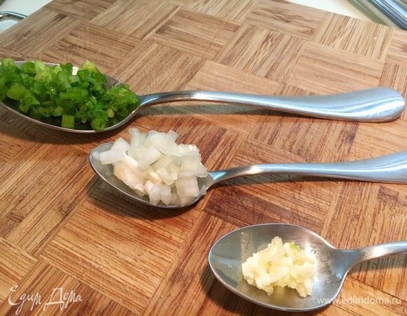 Мелко нашинкуйте зеленый лук, репчатый лук и выдавите чеснок.