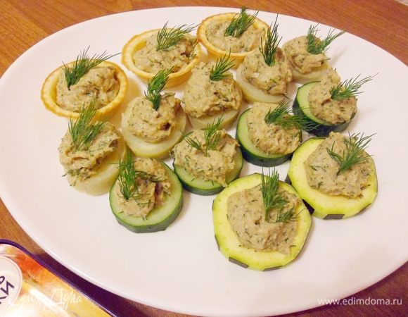 Чайной ложкой выложить печень трески на основу «шапочкой», украсить зеленью.