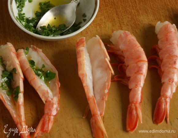 Хвосты (мясо) аргентинских креветок разрезать по средней линии почти до конца. В мисочке смешать по 1 ст. л. оливкового масла и лимонного сока, добавить петрушку, чеснок, соль и перец. Распределить смесь на разрезанные хвосты.