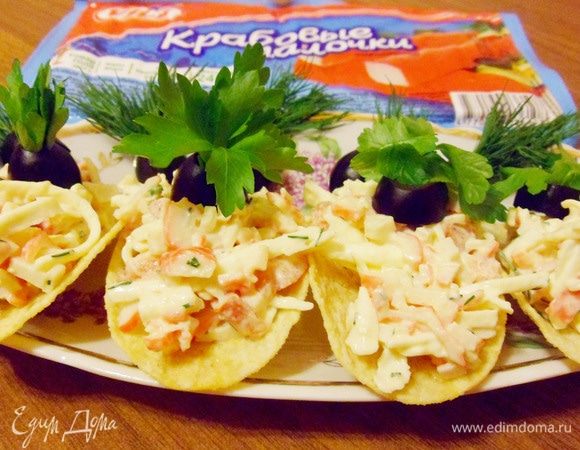 Чайной ложкой выложить на картофельные чипсы. Украсить по своему вкусу зеленью и маслинами.