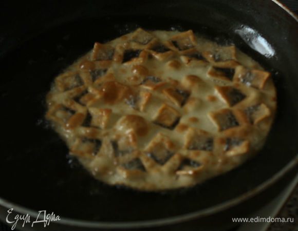 Сначала в течение нескольких секунд обжарьте его с одной стороны, затем двумя большими вилками переверните и обжарьте с другой. Также вилками достаньте диск из кастрюли, подержите над ней, чтобы слить масло, и положите на бумажные полотенца. Сверху нужно промокнуть бумажным полотенцем и накрыть доской. Повторите с остальными дисками, складывая их стопкой под импровизированный пресс.