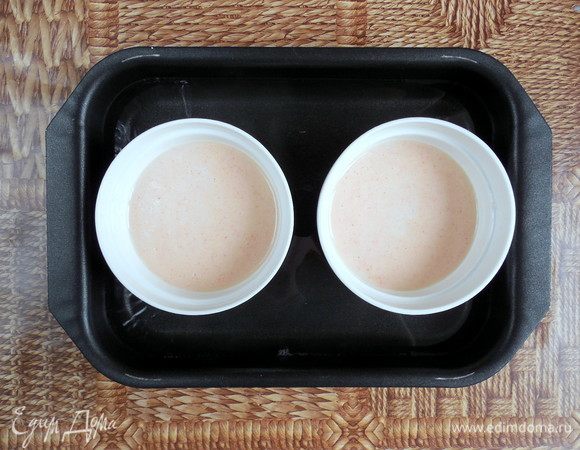 Распределить яичную смесь поровну по формам с карамелью. Пузырьки с поверхности крема можно убрать, аккуратно промокнув их бумажным полотенцем. 
Поместить формы в глубокий противень, а затем налить в него кипяток так, чтобы уровень воды доходил до середины форм. Накрыть противень фольгой и запекать 40-45 мин. (готовность проверить при помощи небольшого ножа, он должен выходить чистым, если проткнуть запеченный крем).