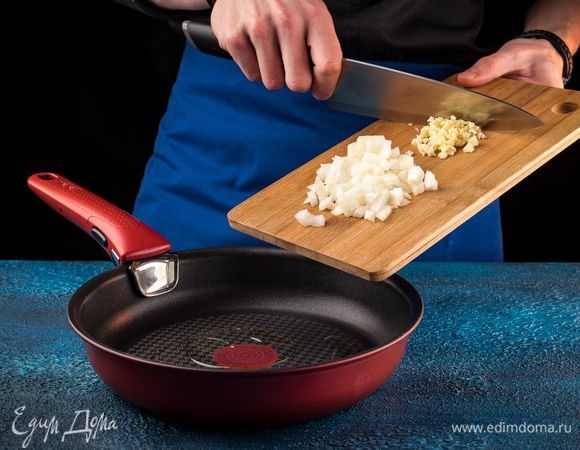 Лук измельчите, чеснок раздавите с помощью пресса. На сковороде разогрейте оливковое масло и поджарьте лук с чесноком до мягкости.