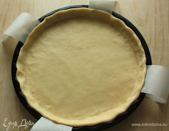 Подготовить 2 круга из пергамента по диаметру формы, один поместить на ее дно.
На присыпанной мукой поверхности тонко раскатать тесто в круг и на скалке перенести в форму. 
Пальцами прижать тесто к бортикам, дно наколоть часто вилкой, закрыть пергаментом. Излишки теста срезать (я взяла неразъемную форму, поэтому на дно положила 2 длинные широкие полоски, чтобы м. б. легко извлечь пирог).