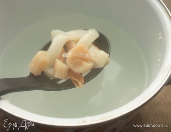 Нарежьте кальмары тонкими кольцами (у меня получается толщина примерно 5 мм), а морские гребешки — на половинки. Опустите морепродукты в кипящий рыбный бульон и варите 2,5-3 минуты. Я помню, как в детстве мы варили кальмары долго-долго, но потом на одном из кулинарных мастер-классов шеф-повар рассказал, что кальмары (полностью размороженные) достаточно готовить 2-2,5 минуты, максимум 3 минуты, чтобы они приготовились и стали мягкими. Если передержать, они становятся резиновыми, и их уже нужно варить дольше, чтобы они вновь стали мягкими.
Готовые морепродукты также достаньте из бульона и быстро обжарьте на небольшом количестве сливочного масла на сковороде (буквально в течение 1 минуты).