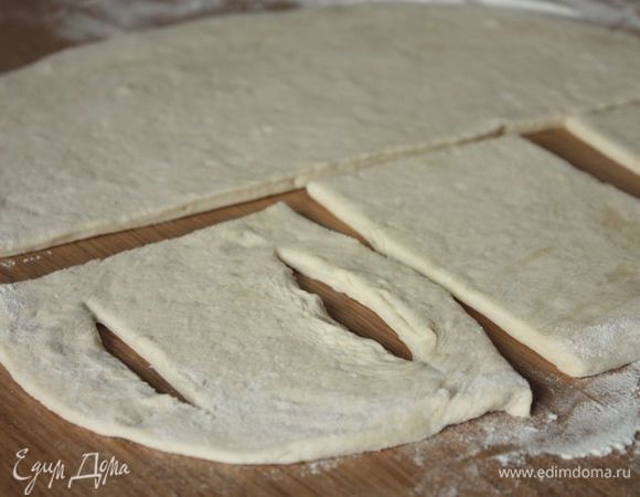 Поднявшееся тесто еще раз обомните и раскатайте. Можно скатать его в колбаску и нарезать на части, а можно раскатать тесто в пласт и нарезать на прямоугольники (размером чуть больше кусков рыбы). В каждом прямоугольнике нужно сделать два отверстия на расстоянии от краев.