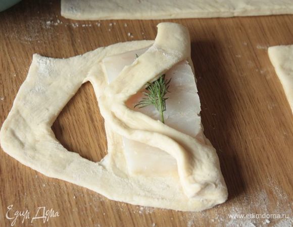 Накройте рыбу одной стороной теста, наискось.